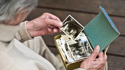 Eine alte Frau sieht sich Fotos aus ihrer Vergangenheit an.